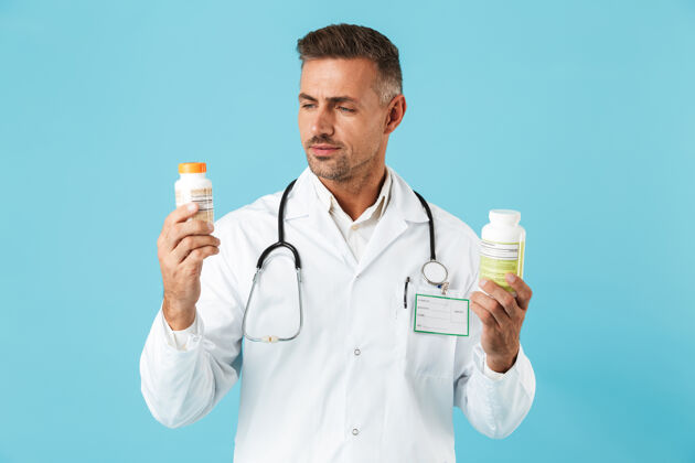 医院一幅美丽的医学专家的画像 身穿白大褂 手里拿着几罐药片 孤零零地站在蓝色的墙上肖像阳性服务