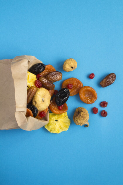 健康食品蓝色背景的纸袋中不同干果的俯视图樱桃超级食品小吃