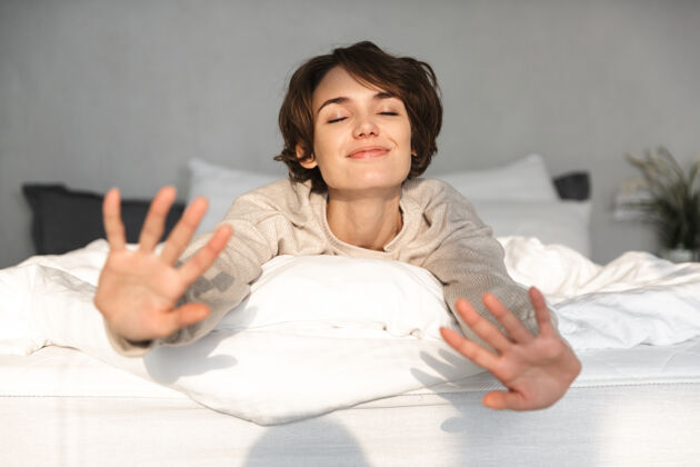 肖像快乐的黑发女人躺在床上 闭着眼睛享受卧室休闲年轻女士