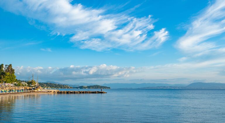 海湾美丽的爱奥尼亚海滩景观 有五颜六色的躺椅 树木和供游客入住的酒店海岸希腊语地中海