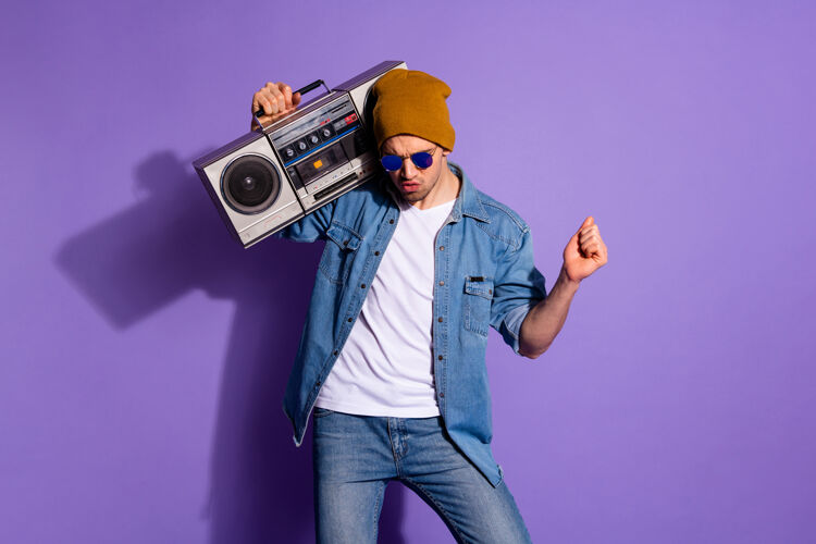 迪斯科照片中的粗心放松时髦的家伙拿着录音机的声音与她的手跳舞乐趣隔离紫色生动的色彩背景音频时尚头饰