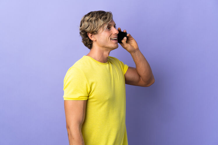 金发孤立的紫色背景下的英国男人用手机交谈男人电话美国