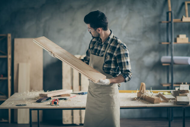 抛光认真自信的工人修理家具拿着木刨花板在家里的车库里试着光滑雕刻看看长度人严肃