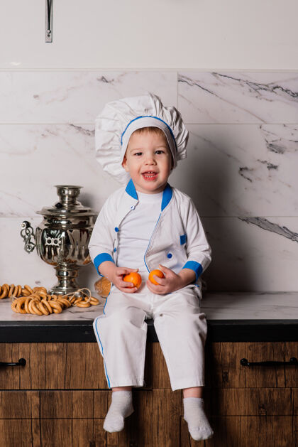 有趣小可爱的厨师拿着餐具坐在厨房里 双胞胎兄弟 橘子 百吉饼人孩子自然