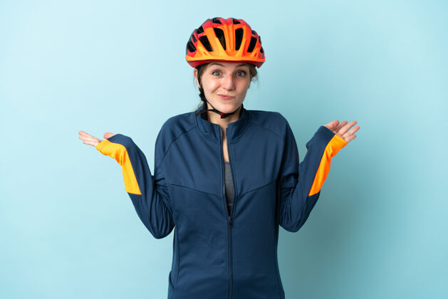 不确定一位年轻的骑自行车的女士 站在蓝色的背景上 举手的时候有疑虑困惑头盔自行车
