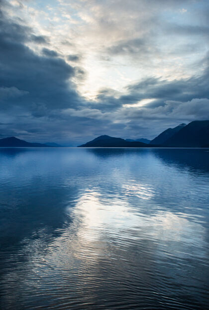 野生自然在阿拉斯加的峡湾里 云层反射在水中海洋风景日落