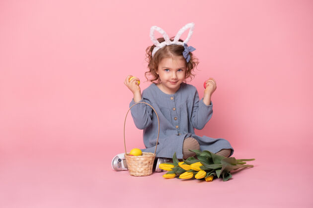 肖像有趣的小女孩戴着兔子耳朵 手里拿着粉色的复活节彩蛋衣服节日惊喜
