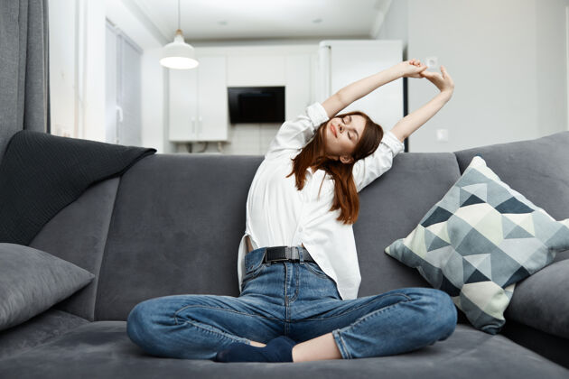 房间女人坐在沙发上弯腿舒适的公寓休息舒适健康