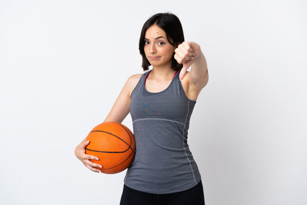 失败打篮球的年轻女子被隔离在白墙上 拇指朝下 表情消极欺骗年轻不同意