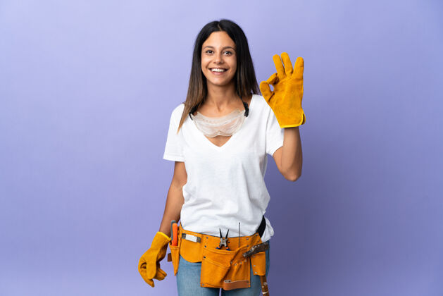 女人被隔离在紫色墙壁上的年轻电工女士用手指显示ok标志工匠乐观年轻