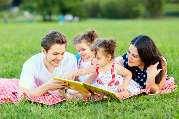 父母一个幸福的家庭正在公园里看书女孩美丽欢乐
