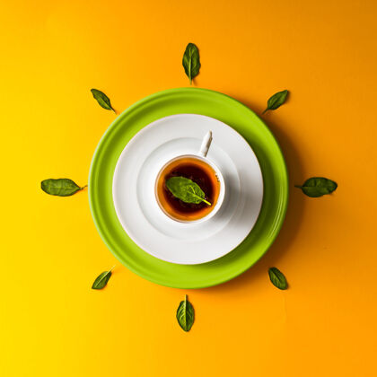 现代茶杯里的茶 橘子上有绿叶墙.时间概念桌子铺设头顶
