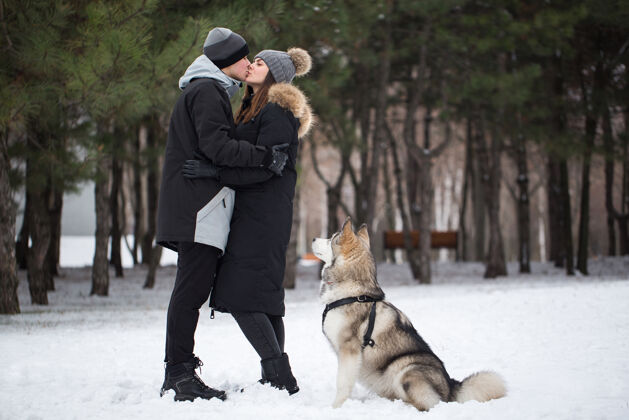 宠物美丽的家庭 一个男人和一个女孩在冬天的森林里狗玩和狗西伯利亚哈士奇活动外面雪