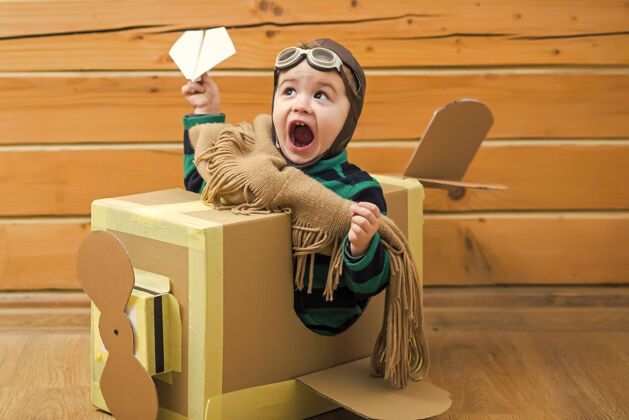 墙壁小男孩在木屋里玩纸板飞机飞机玩具人