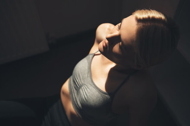 家庭健身房上图是一位穿着运动服的白人妇女在家健身时在地板上休息的照片活跃年轻模特