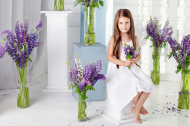 时尚美丽动情的小女孩坐在紫罗兰花丛中室内的花饰美丽微笑快乐