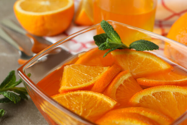 碗在灰色的桌子上放一碗橘子果冻和橘子片的甜点概念 特写冷美味吃