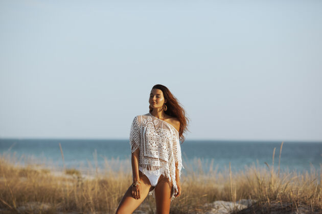 泳装完美的年轻波西米亚女子站在沙滩上对美丽的波基复制空间高加索时尚束腰外衣