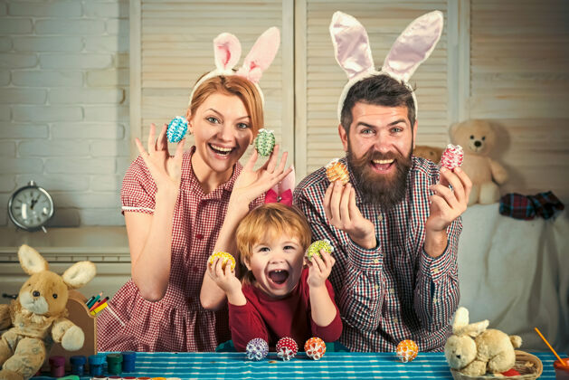 庆祝妈妈 爸爸和儿子在画画鸡蛋快乐复活节家人可爱戴着兔子耳朵的小孩小耳朵妈妈