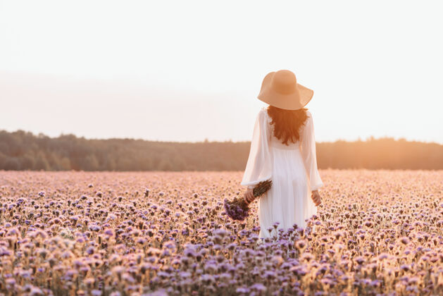 女士一个在薰衣草地里的漂亮女孩一个穿着白色裙子手拿花束的普罗旺斯风格的漂亮女人欢乐多彩普罗旺斯