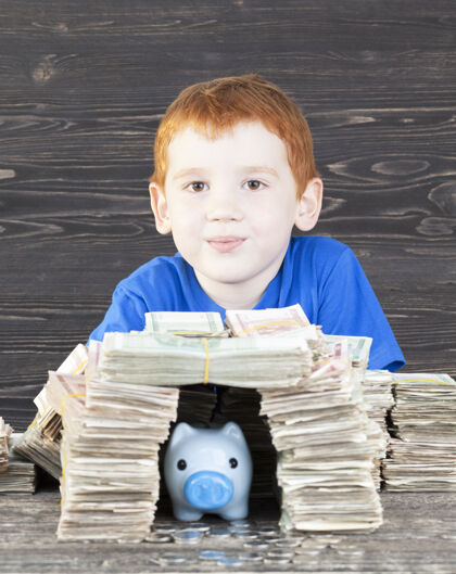 小男孩用硬币为他的蓝色小猪存钱罐盖了一屋子的纸钱 特写投资猪脸