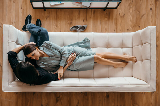 浪漫这对年轻夫妇正在豪华的白色沙发上放松沙发视图从上面婚礼公寓感情
