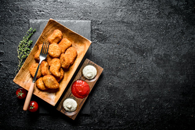 美式用叉子 百里香和各种酱汁放在盘子里的鸡块放在黑木桌上美味面包准备