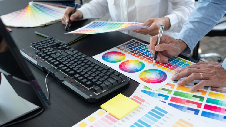 办公桌在创意办公室的办公桌上 平面设计师团队正在使用色板进行网页设计 使用平板电脑和手写笔编辑艺术品工作计算机显示器