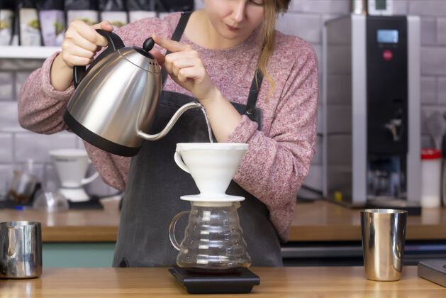 磨坊咖啡师用咖啡壶做浓咖啡漏斗在咖啡池里煮咖啡的过程校准器溢出咖啡从水壶中通过过滤漏斗流出工人牛奶制作