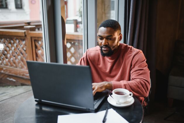 男人有思想和专注的年轻非裔美国文案作家的肖像电脑在线年轻
