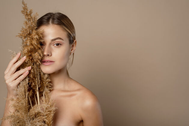 皮肤护理一个漂亮的年轻裸体女人的特写美女肖像 棕色头发孤立在米色背景上 拿着干头发药草皮护理理念女孩小麦新鲜