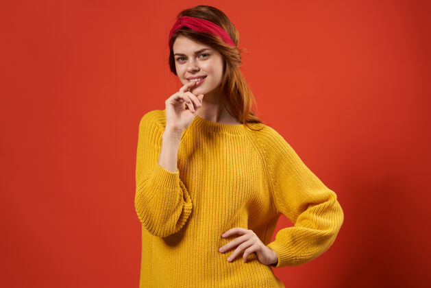 微笑穿着黄色毛衣的漂亮女人红色头带嬉皮街头风格的红墙姿势女士时髦