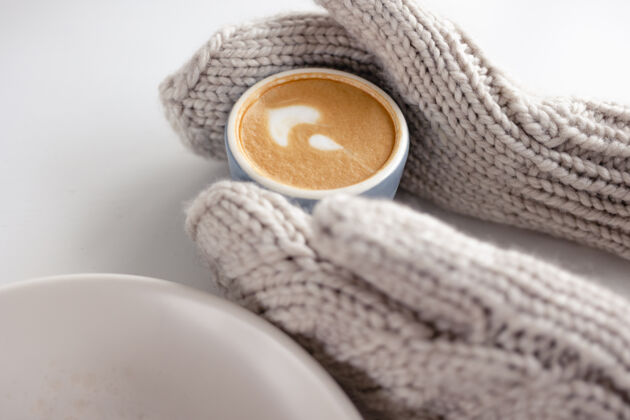 热女人戴手套的手拿着一个咖啡杯在一张白色的桌子上特写早餐女性乡村