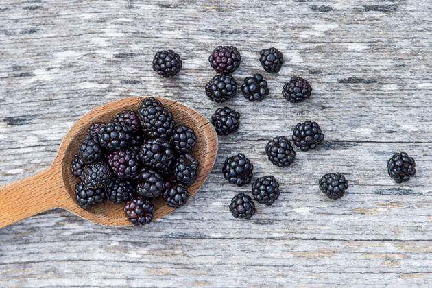 成熟的在古老的木制背景上 用木勺盛着成熟的黑莓组美味抗氧化剂