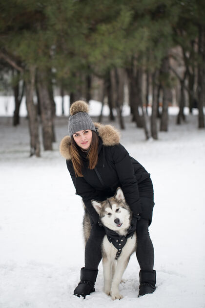 朋友冬天森林里美丽的女孩狗玩和狗西伯利亚哈士奇活动哈士奇欢呼