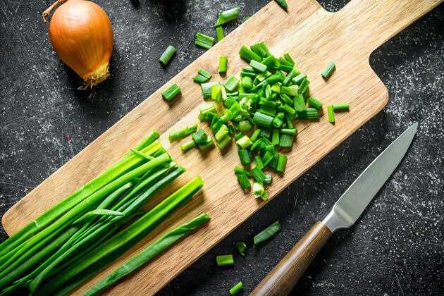 沙拉用刀在砧板上切洋葱 在黑木桌上切洋葱韭菜素食绿色