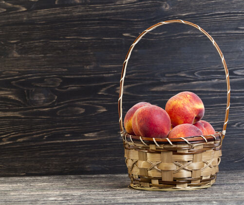 营养成熟可口的桃子放在篮子里 站在黑色的木桌上美味篮子配料