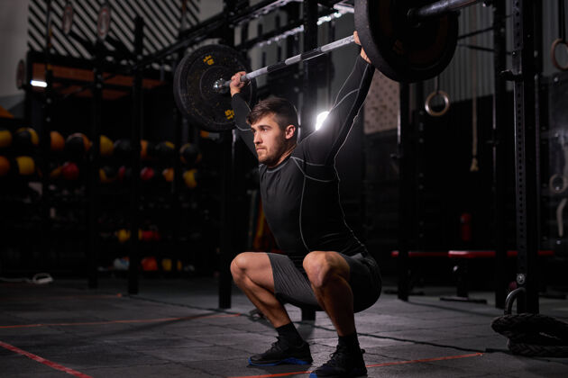 运动运动健将杠铃年轻高加索肌肉男健美运动员在黑暗健身房做举重锻炼 使用运动设备举重锻炼运动员