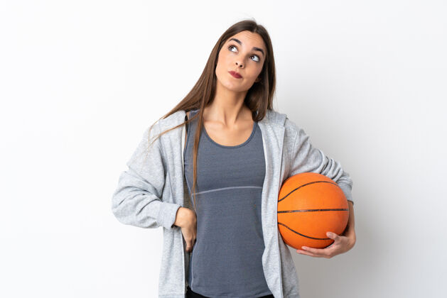 运动员年轻女子打篮球孤立在白色的背景和仰望运动健身爱好
