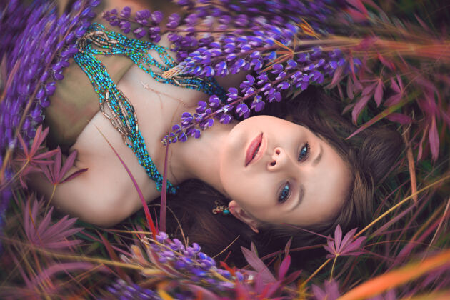 夏天美丽的女孩躺在羽扇豆花里女性肖像人