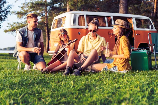 女性在夏天的节日里 时髦的朋友们坐着露营车户外热复兴
