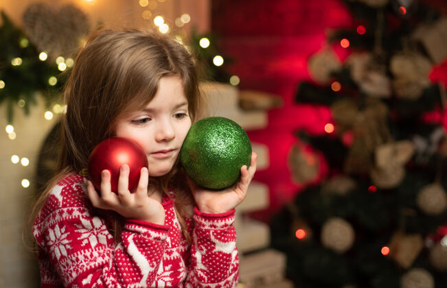 场景可爱的小女孩拿着圣诞树旁的圣诞装饰品梦想礼物模型