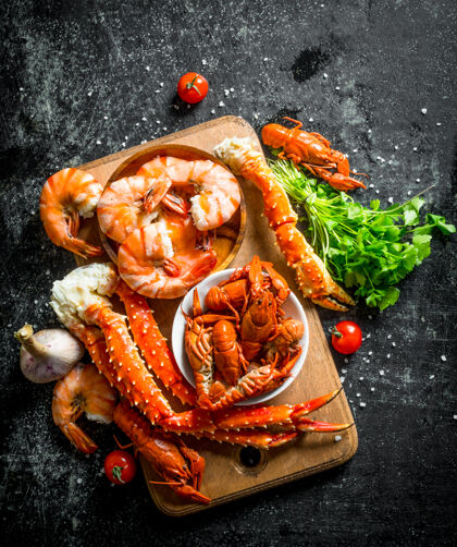 美食海鲜香喷喷的虾 小龙虾和螃蟹放在木板上 上面放着香草和樱桃番茄烹饪餐厅红