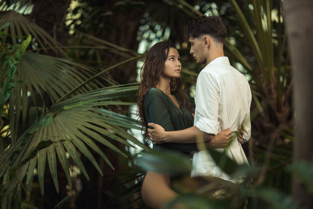 年轻一对浪漫的情侣在热带丛林中的异国植物中模特成人雨林