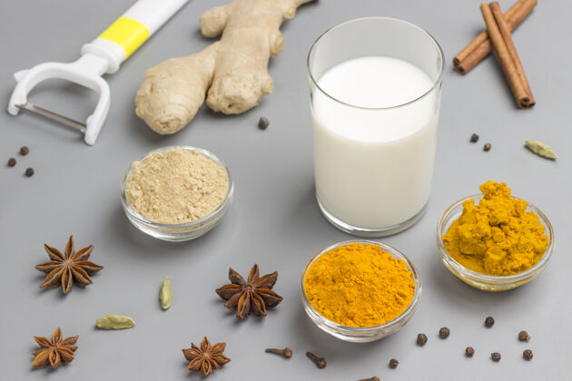 草药牛奶在玻璃与配料烹饪印度饮料姜黄饮料豆蔻配料治疗