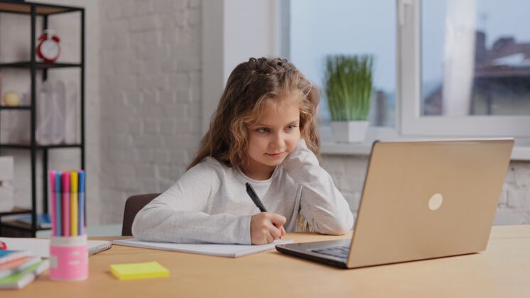 童年女生有网上课 在练习本上写字 做作业作业.距离学习互联网视频室内