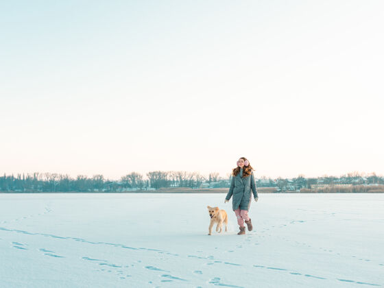金毛猎犬冬季公园里的一位年轻女子和她的金毛狗散步寻回犬友谊宠物和人类拉布拉多公园年轻