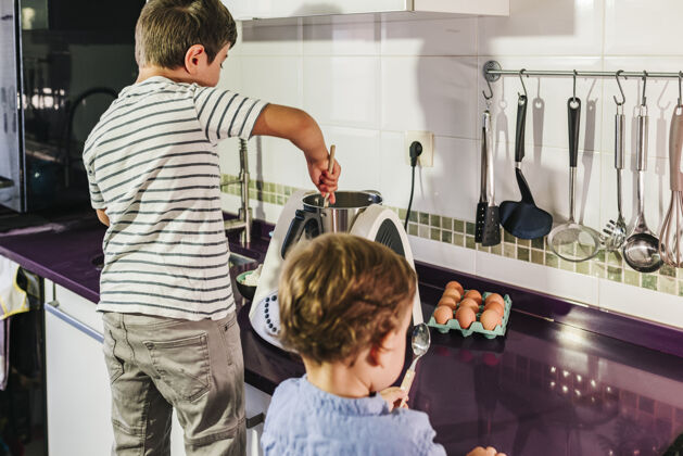 微笑两个孩子在用厨房机器人做煎饼房子用餐甜蜜