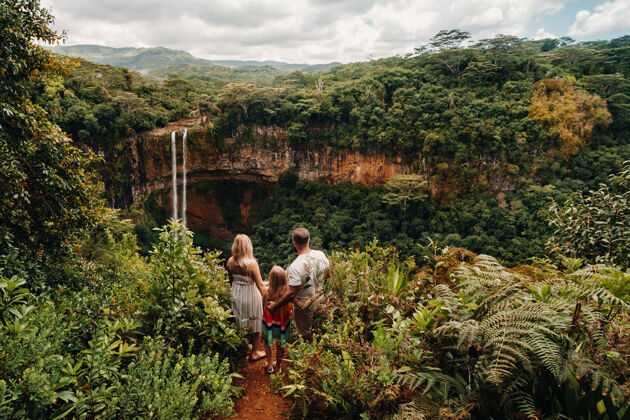 家庭一个家庭 一个男人 一个女人和一个女儿 站在一个悬崖边上靠近一个瀑布在毛里求斯岛上的查马雷尔公园海岛之旅悬崖幸福家庭