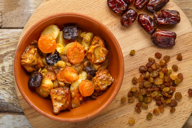 胡萝卜一盘犹太料理 胡萝卜 红枣和火鸡肉放在一个木盘上 旁边撒上葡萄干和红枣熟食节日犹太